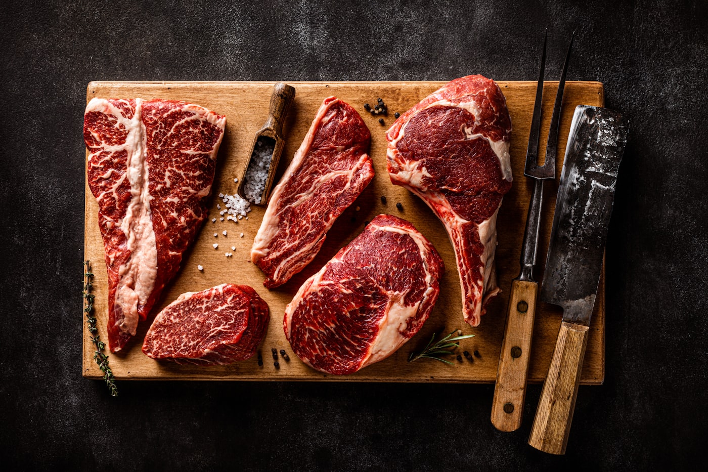 Cuts of fresh red meat on a wooden board.