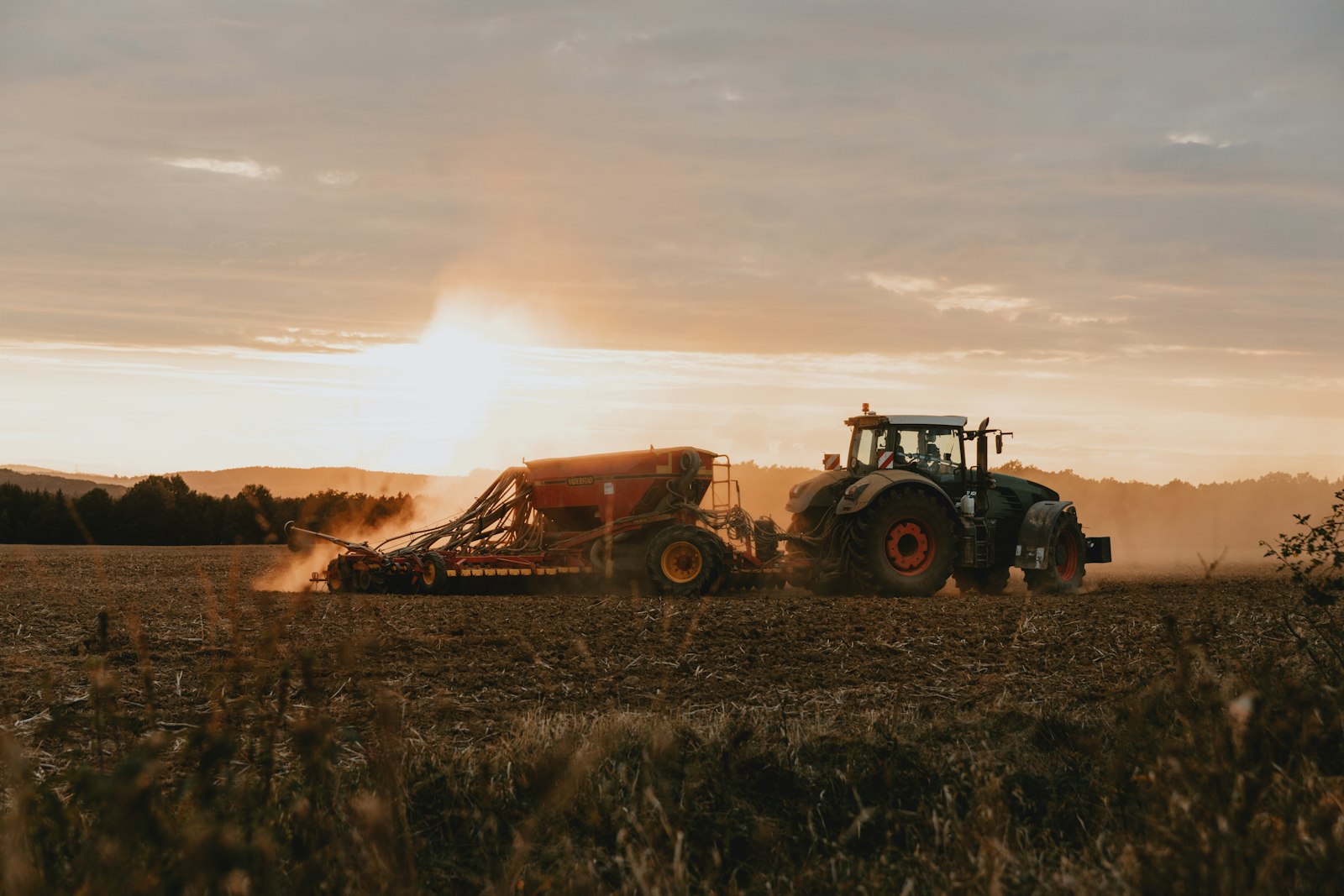 A tractor working a field in the last light of the day.